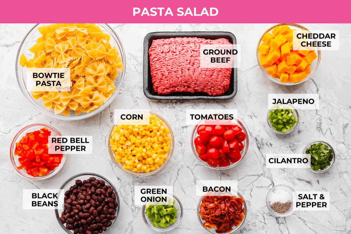 Yeehaw! My cowboy pasta salad is loaded with beef, bacon, beans, and all the fixings for all you cowboy lovers. You'll get all the flavors of the Wild West tossed in the tastiest cowboy salad dressing. Overhead shot of labeled pasta salad ingredients.