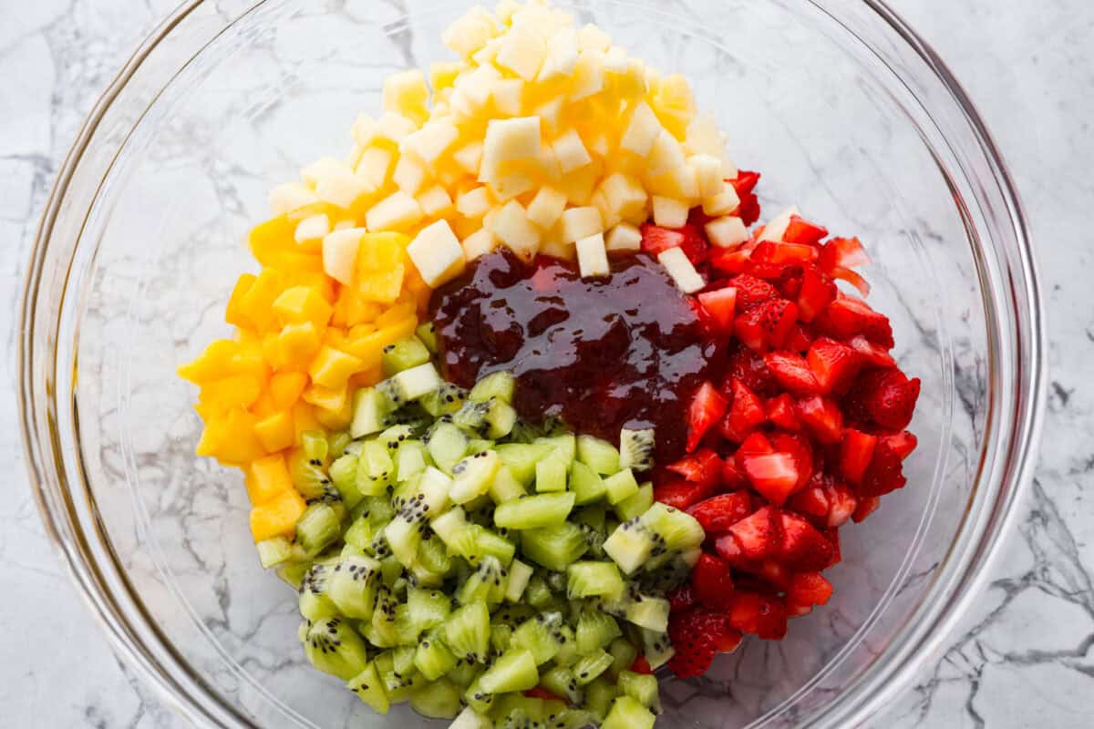Vibrant fruit salsa is a fresh, juicy twist on your favorite snack! Sweet berries, tropical mango, and a splash of lime always steal the spotlight! Especially when served with crispy cinnamon chips! Raspberry jam added to the bowl of diced fruit.