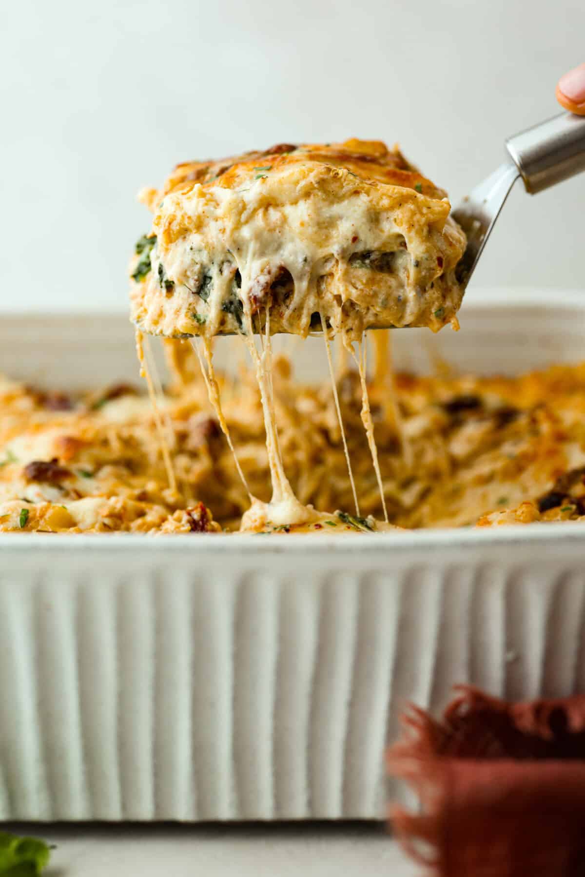 They don’t call it Marry Me Lasagna for nothing! One bite of the creamy sauce, tender chicken, and melty cheese, and everyone will be saying, Side shot of someone pulling a slice of marry me lasagna out of the pan with cheesy sauciness stretching from the main casserole.