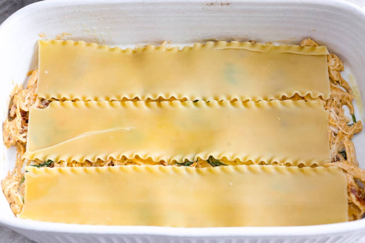 They don’t call it Marry Me Lasagna for nothing! One bite of the creamy sauce, tender chicken, and melty cheese, and everyone will be saying, Bottom layer of meat sauce with lasagna noodles on top.