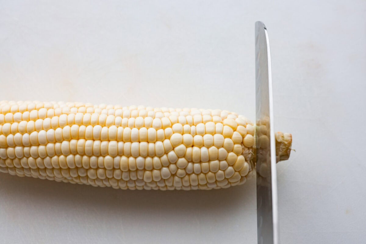 Someone cutting the stalk off the end of the cob. 