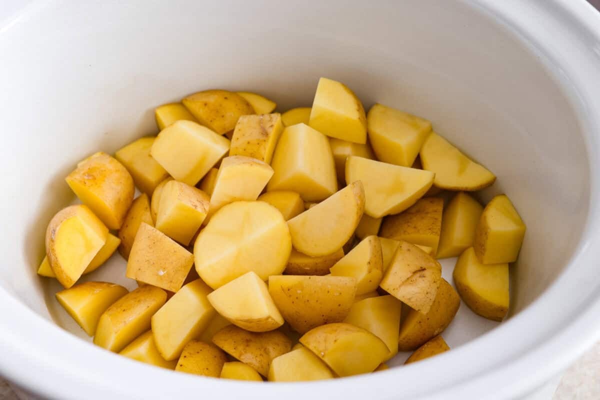 Potatoes sliced and placed in the bottom of the slow cooker. 