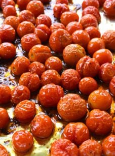 Roasted cherry tomatoes on a lined baking sheet.