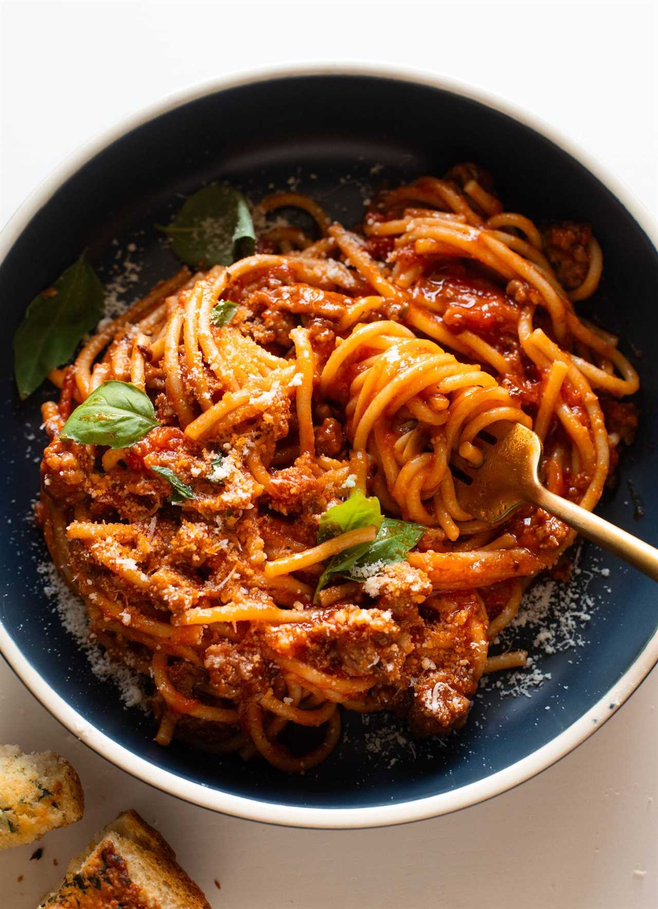 Instant Pot Spaghetti in a bowl topped with basil and parmesan.