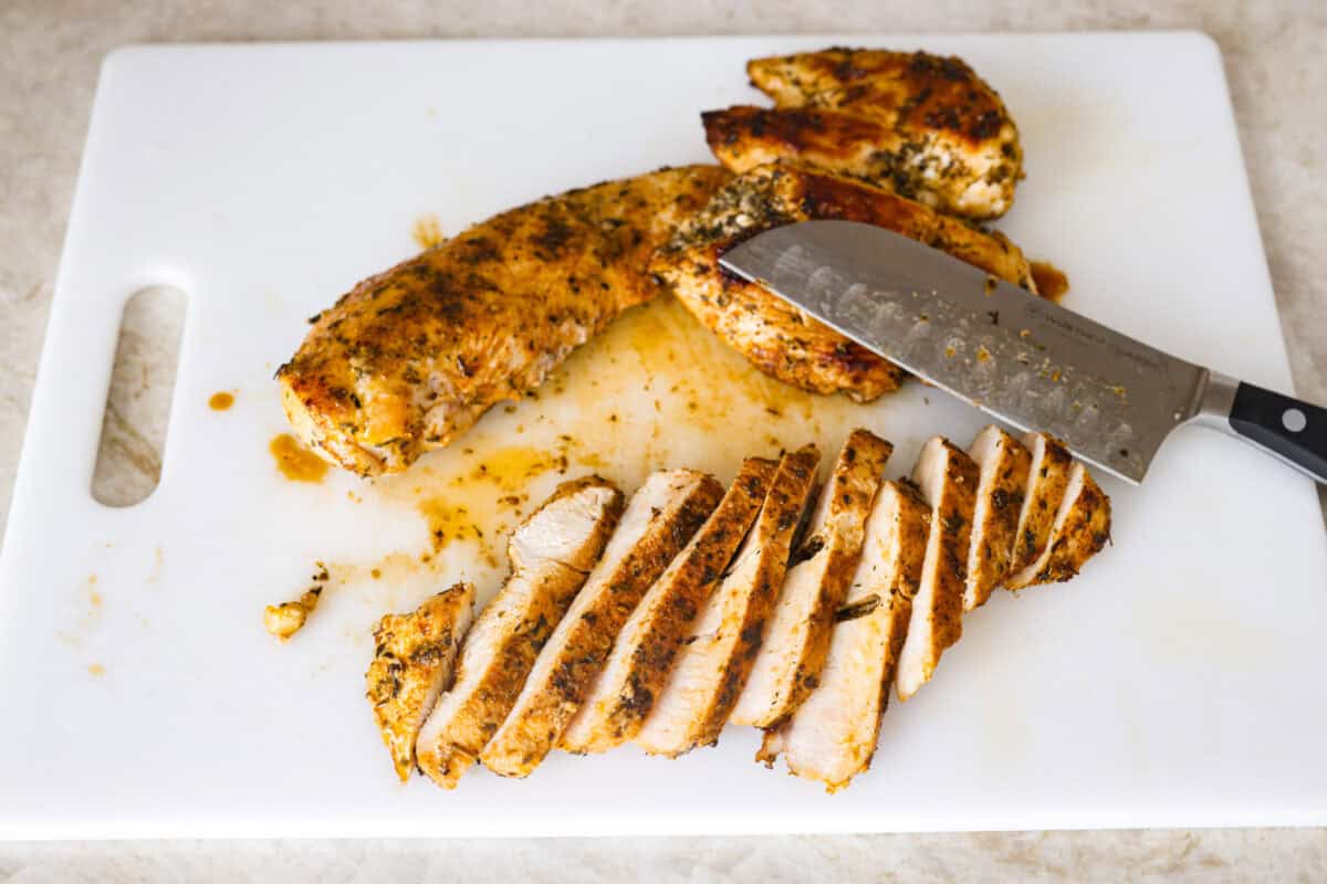 Overhead shot of cooked chicken sliced on a cutting board. 
