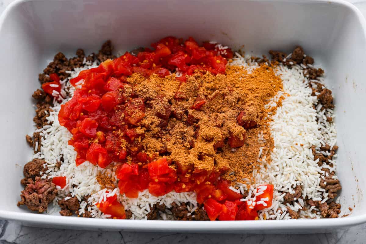 Cooked ground beef in the bottom of a casserole dish topped with minute rice, Rotel and taco seasoning. 