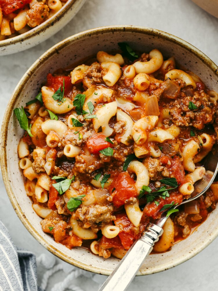 American goulash is an easy, old-fashioned, and comforting meal that is insanely delicious and perfect for the cold winter months. Everything cooks in one pot, even the pasta! A bowl of American goulash with a silver spoon.
