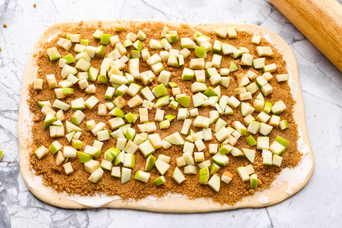 Cinnamon sugar mixture and apple slices spread over the butter on the dough. 