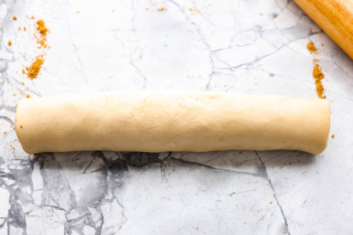 Caramel apple cinnamon roll dough and filling rolled up into a log. 