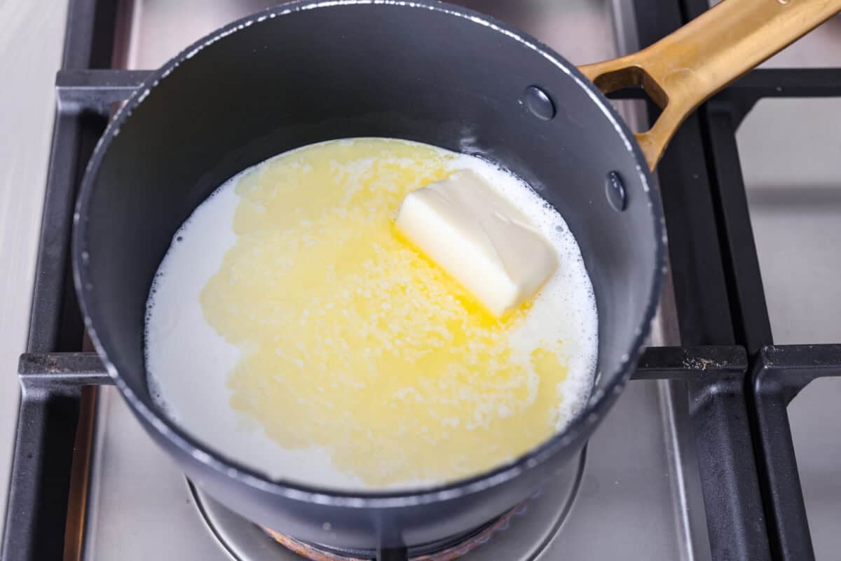 Milk and butter melting in a pot on the stove. 