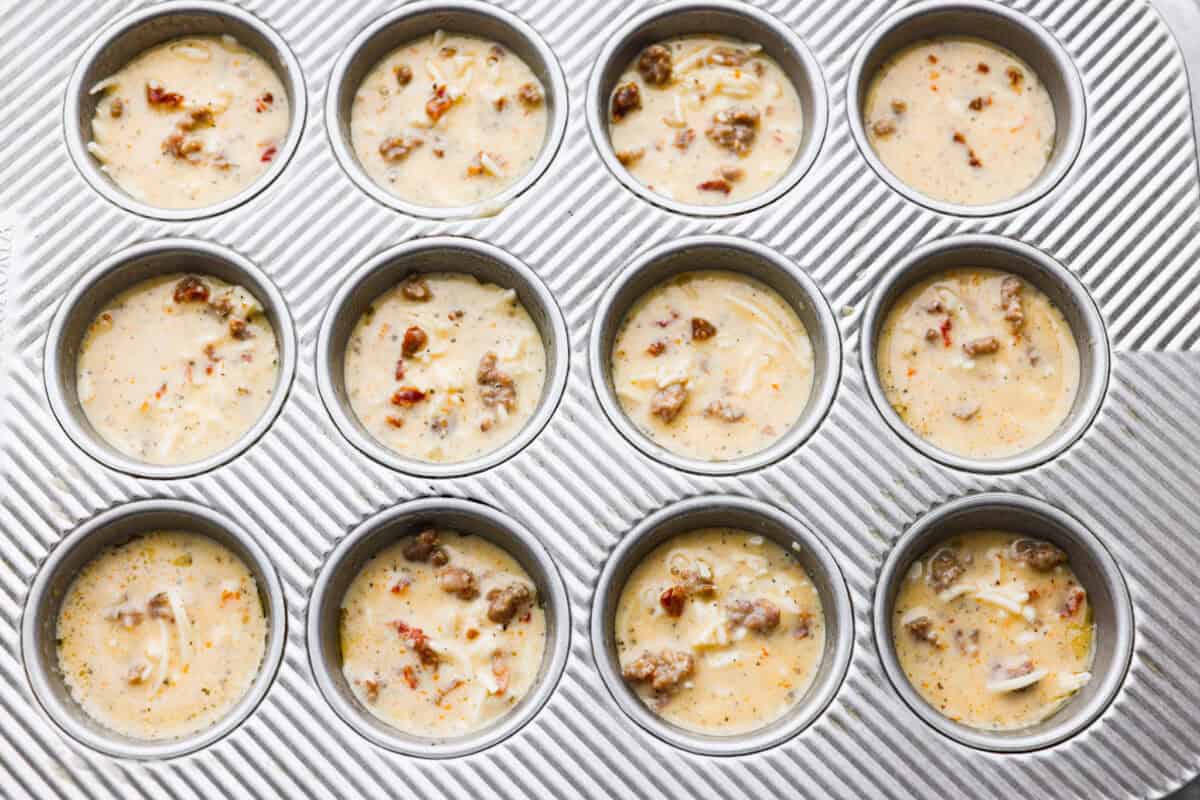 Sausage and egg mixture added to muffin tin, ready to be baked.
