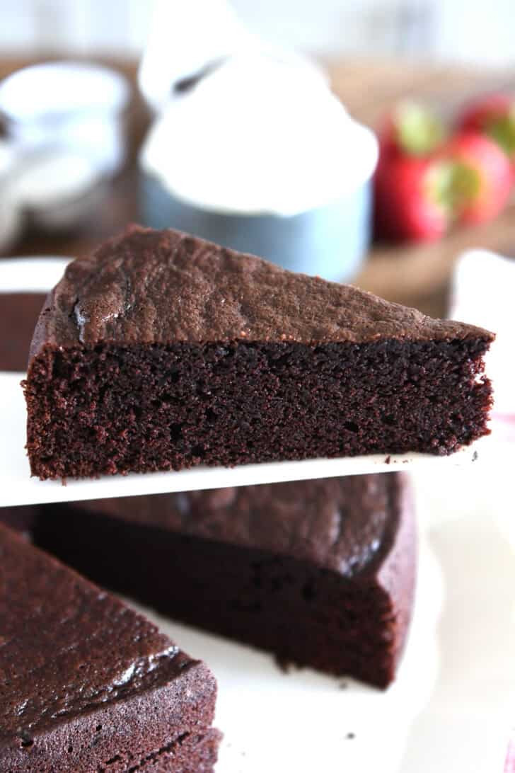 Triangle slice of chocolate olive oil cake on white cake server.