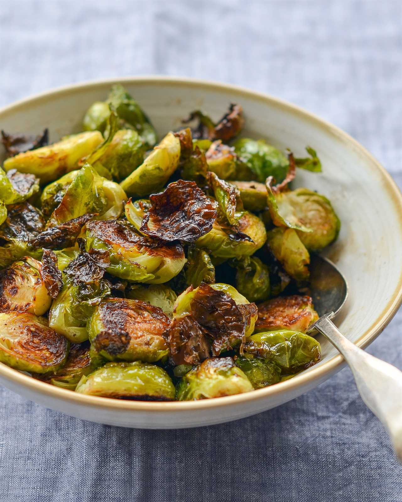 Spoon in a bowl of roasted brussels sprouts with balsamic vinegar and honey.