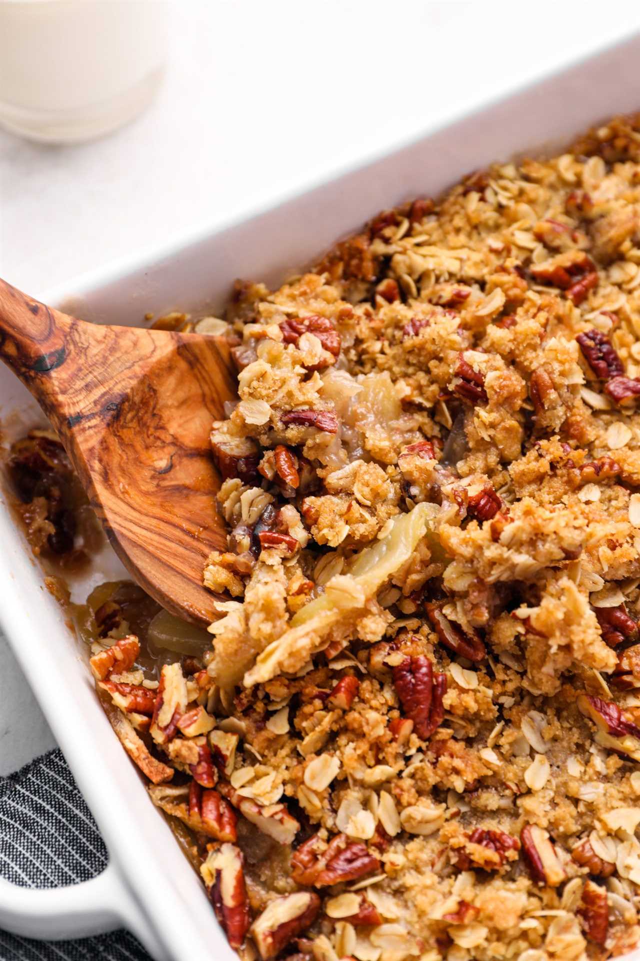 Wooden spoon serving apple crisp.