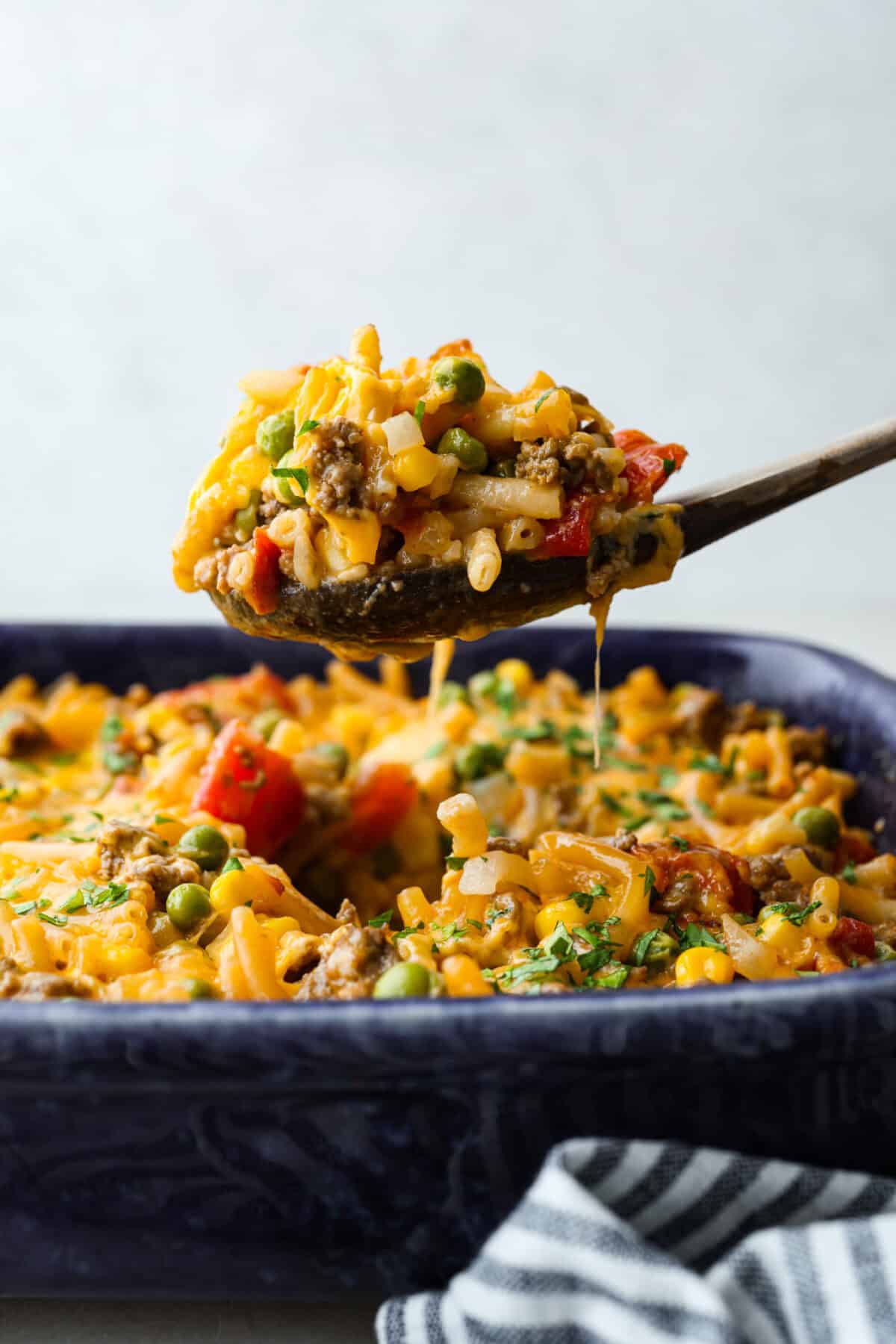 Shipwreck casserole is the ultimate “use what you’ve got” comfort food! Layer it with rice, potatoes, or pasta, toss in any veggies on hand, and make it as cheesy as you like. It’s hearty, budget-friendly, and nearly impossible to mess up! Side shot of someone lifting a scoop of shipwreck casserole from the baking dish.