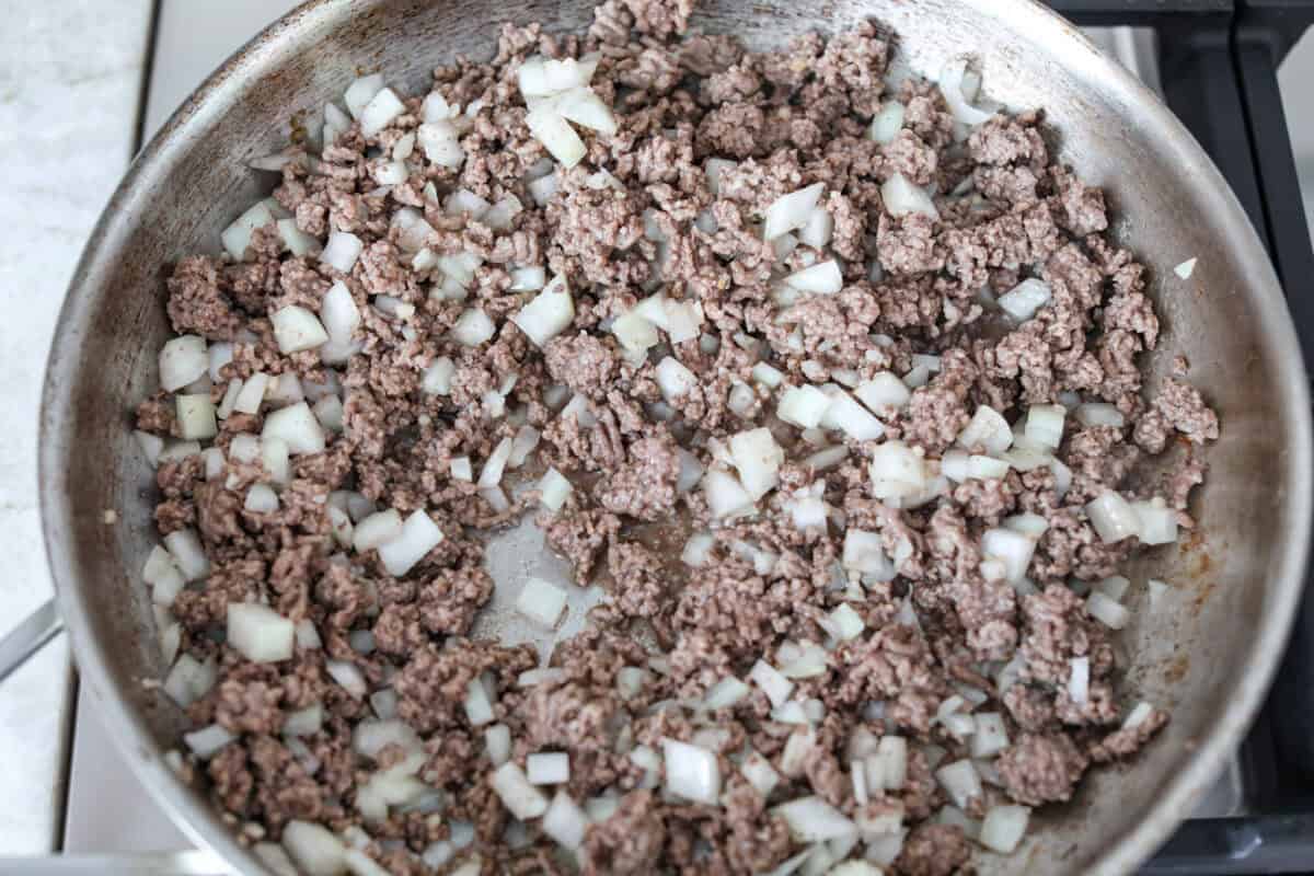 Shipwreck casserole is the ultimate “use what you’ve got” comfort food! Layer it with rice, potatoes, or pasta, toss in any veggies on hand, and make it as cheesy as you like. It’s hearty, budget-friendly, and nearly impossible to mess up! Ground beef and onions cooking in a skillet.