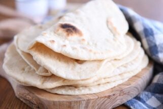 Folded piece of sourdough flatbread on stack of other flatbread.