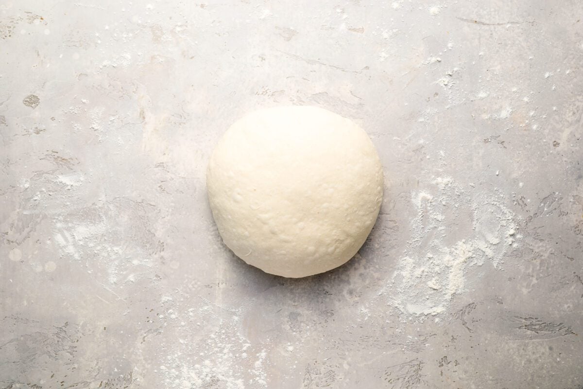 sourdough bread dough shaped into ball on floured surfaced