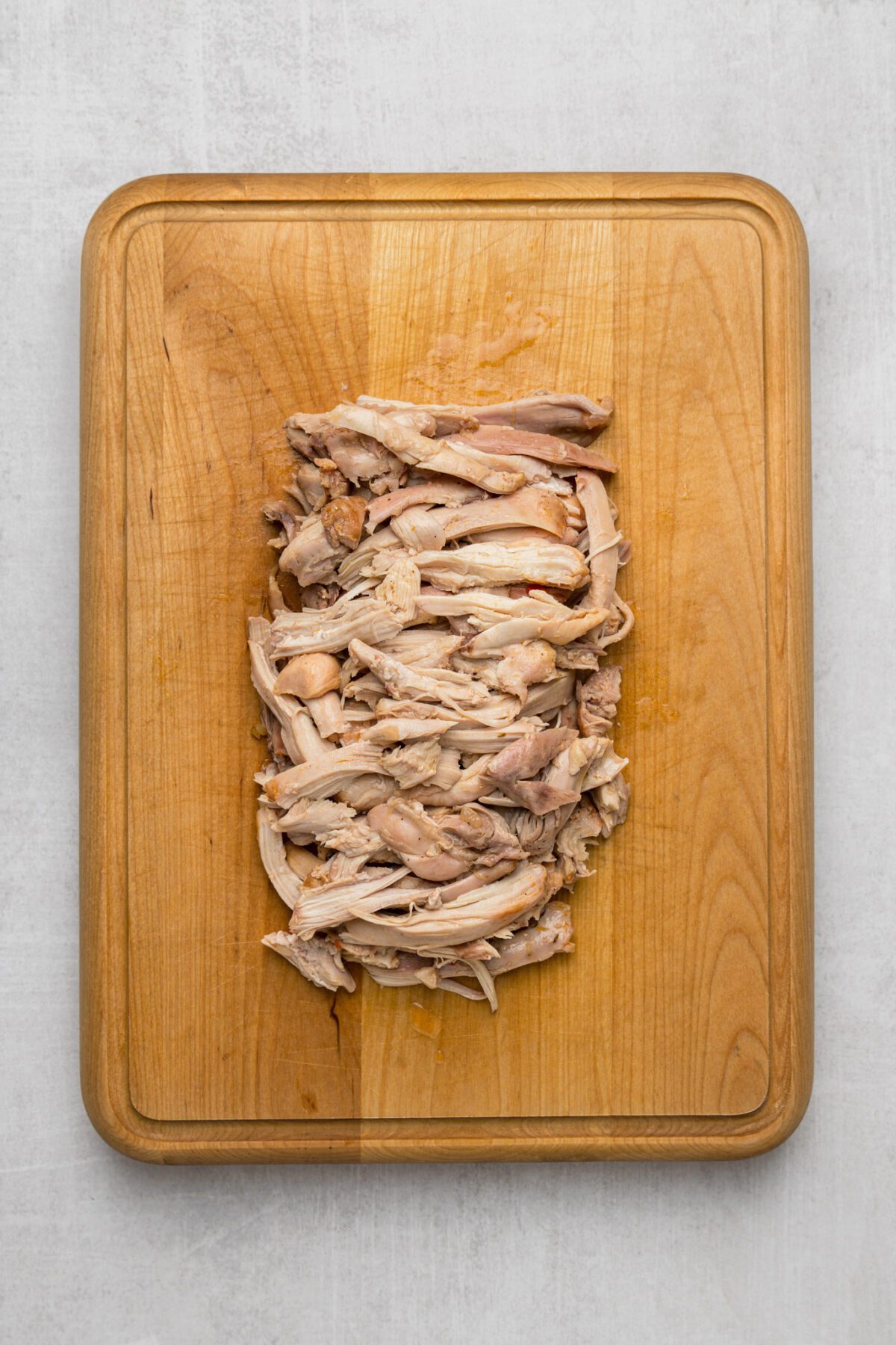 shredded chicken thighs on cutting board