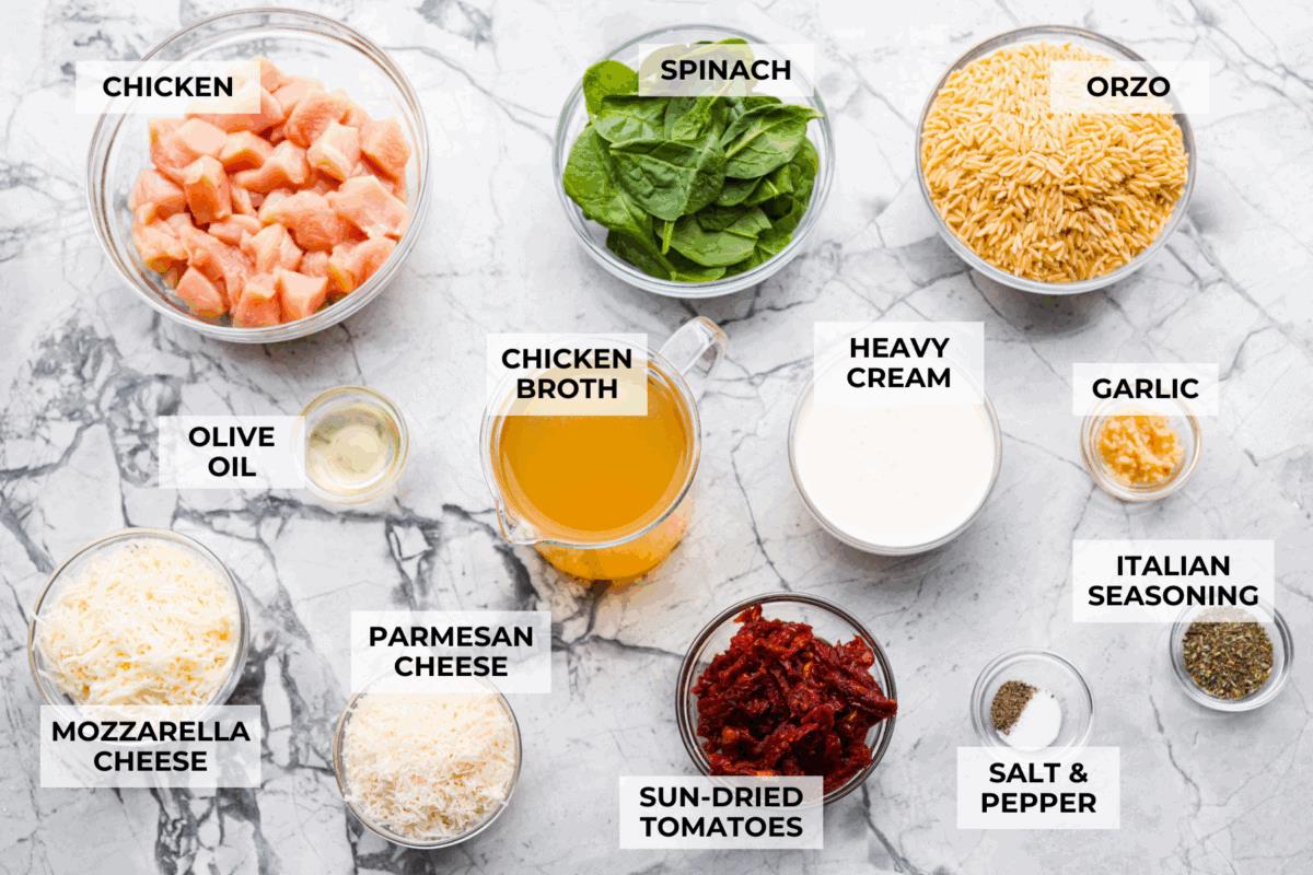 This creamy Tuscan chicken orzo bake is the kind of dinner you’ll want on repeat! Tender chicken, orzo, and sun-dried tomatoes bake together in one pan for an easy, comforting weeknight meal. Overhead shot of labeled tuscan chicken orzo bake ingredients.