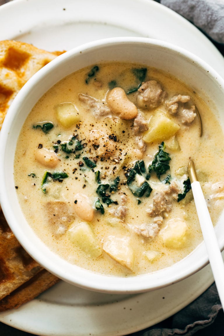 Sausage, kale, and white bean soup in a bowl with a spoon.