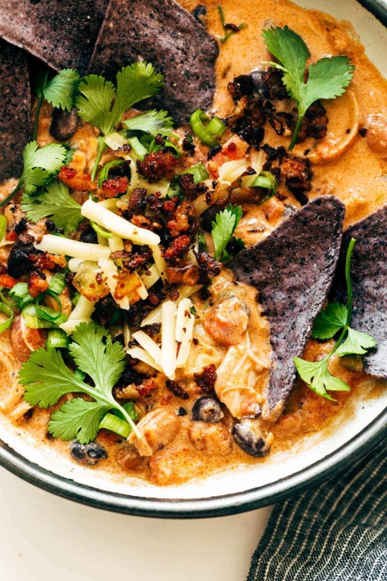 White chicken chili in a bowl with tortilla chips on top.