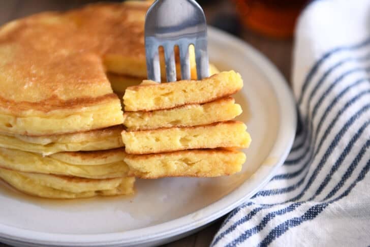 Four triangle slices cut out of stack of four pancakes on gray plate.