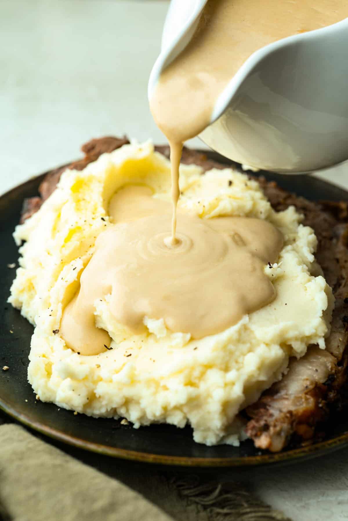 Someone pouring sour cream gravy over mashed potatoes. 