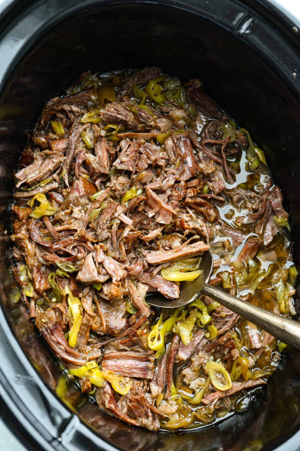Crockpot with slow cooker Italian beef cooked and shredded inside. 