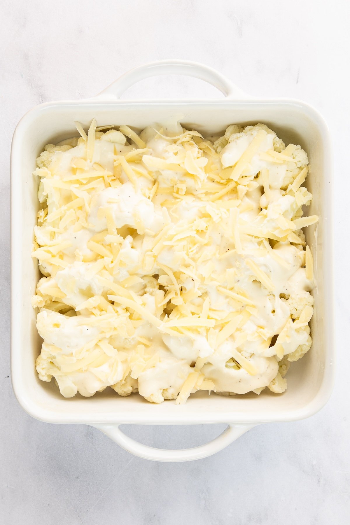 8-inch square baking dish with gruyere spread over cauliflower and bechamel sauce.