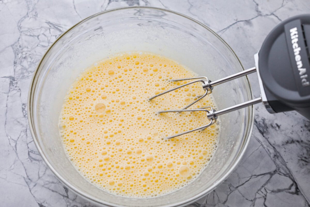 Someone using a hand mixer to whip up the eggs and sugar. 