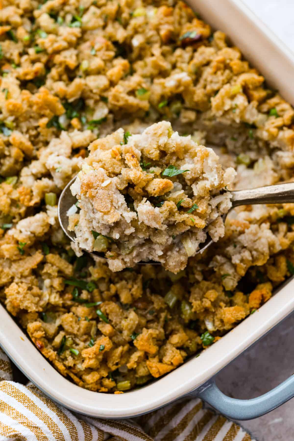 Someone lifting a scoop of cooked 5-ingredient stuffing out of the baking dish.