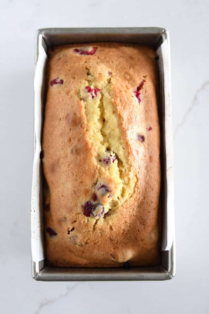 Top down view of baked loaf of cranberry orange bread in standard loaf pan.