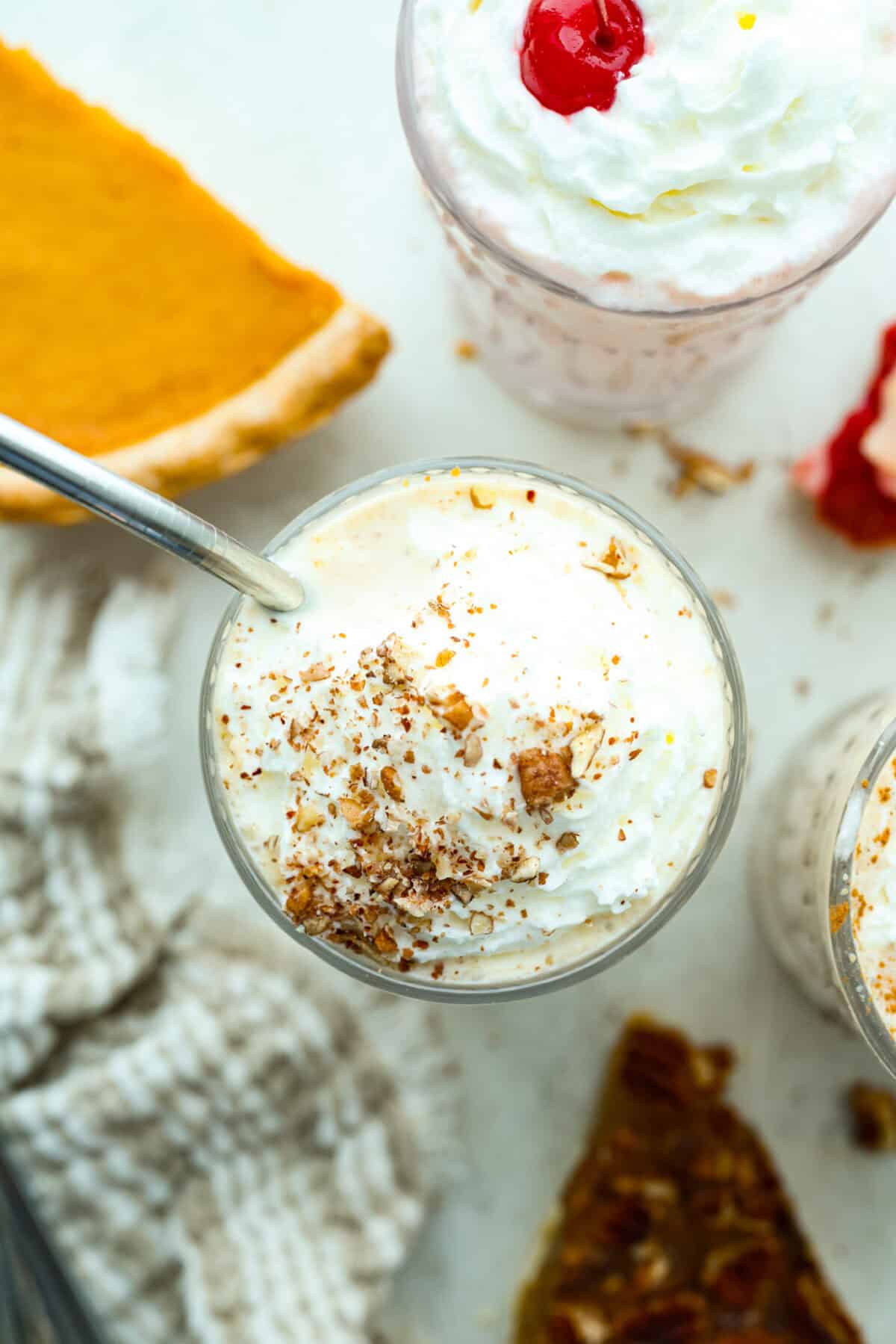 Top down picture of pie milkshakes garnished with whipped cream and nuts. 