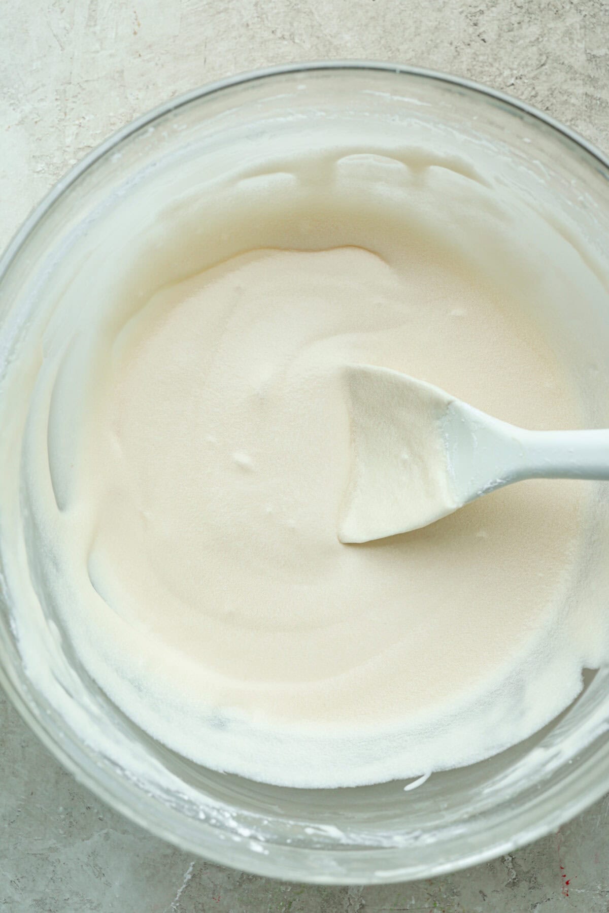Bowl of Cinnamon roll icing with a silicone spoon. 