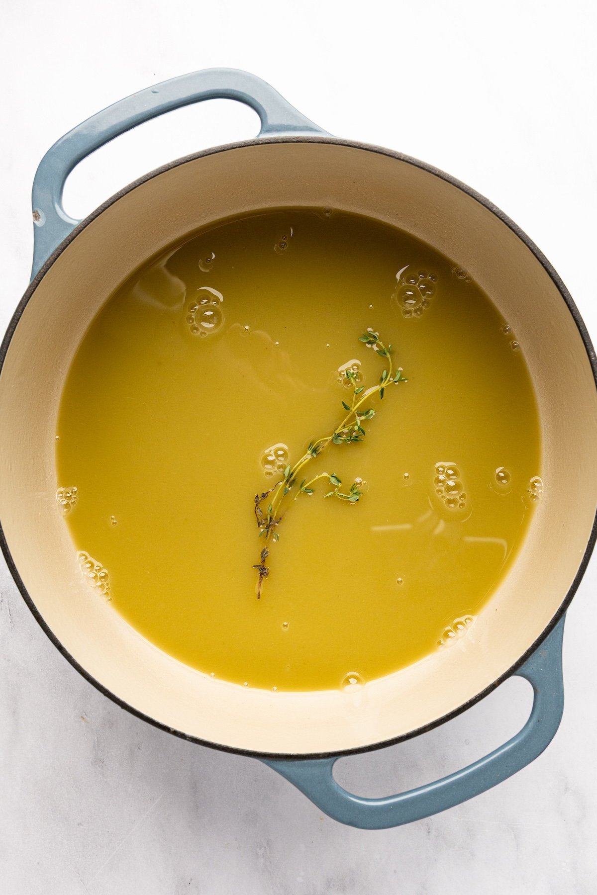 chicken broth and thyme in Dutch oven