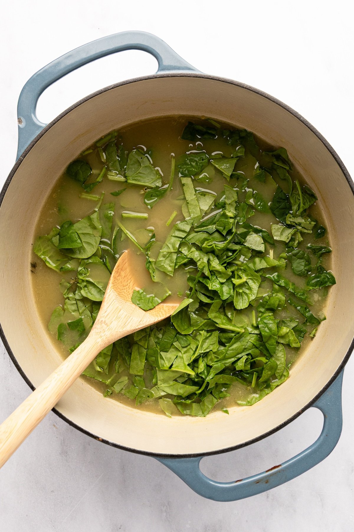 spinach added to broth in Dutch oven