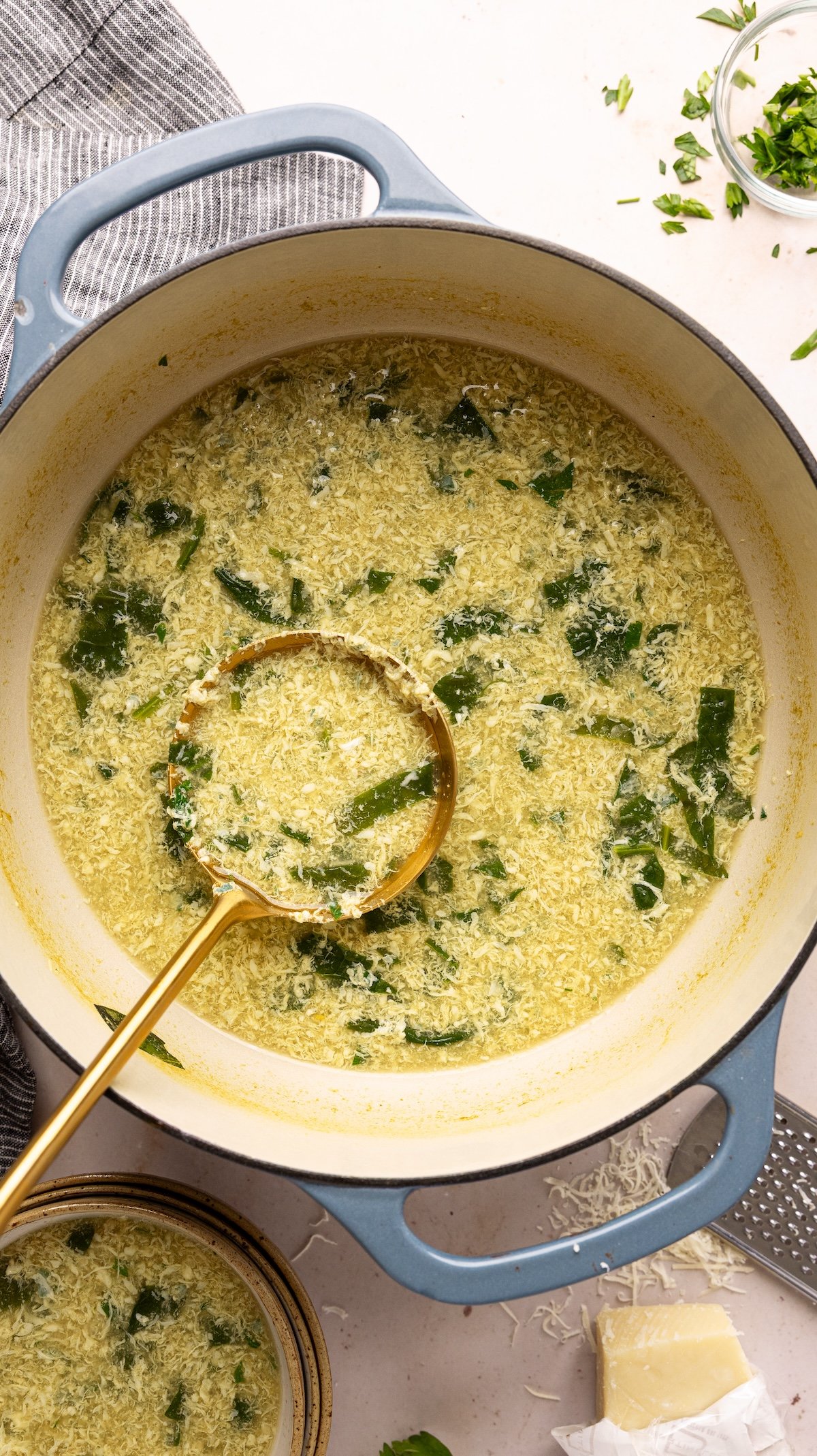 stracciatella soup in Dutch oven with ladle