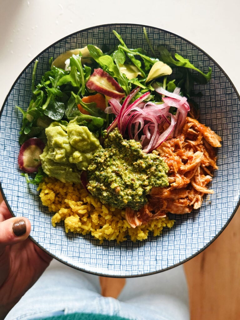 Crockpot chicken in a bowl with toppings.
