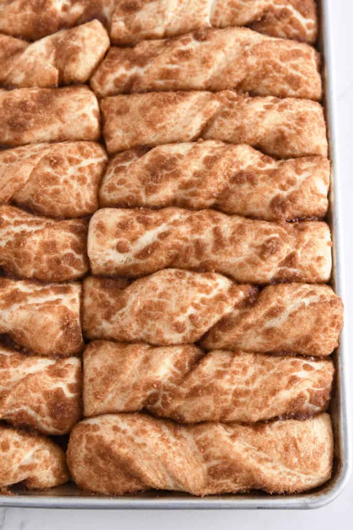 Close up shot of cinnamon sugar twists on half sheet pan after baking.