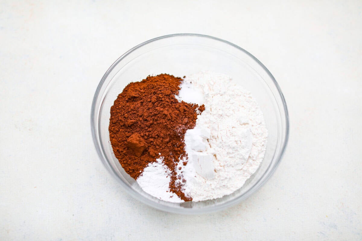 Mixing bowl with flour, baking soda, baking powder, salt and cocoa powder in a mixing bowl. 