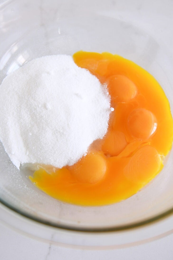 Glass bowl with egg yolks and white sugar.