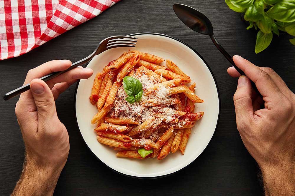 close up of gourmet pasta with marinara sauce garnished with fresh basil and parmesan