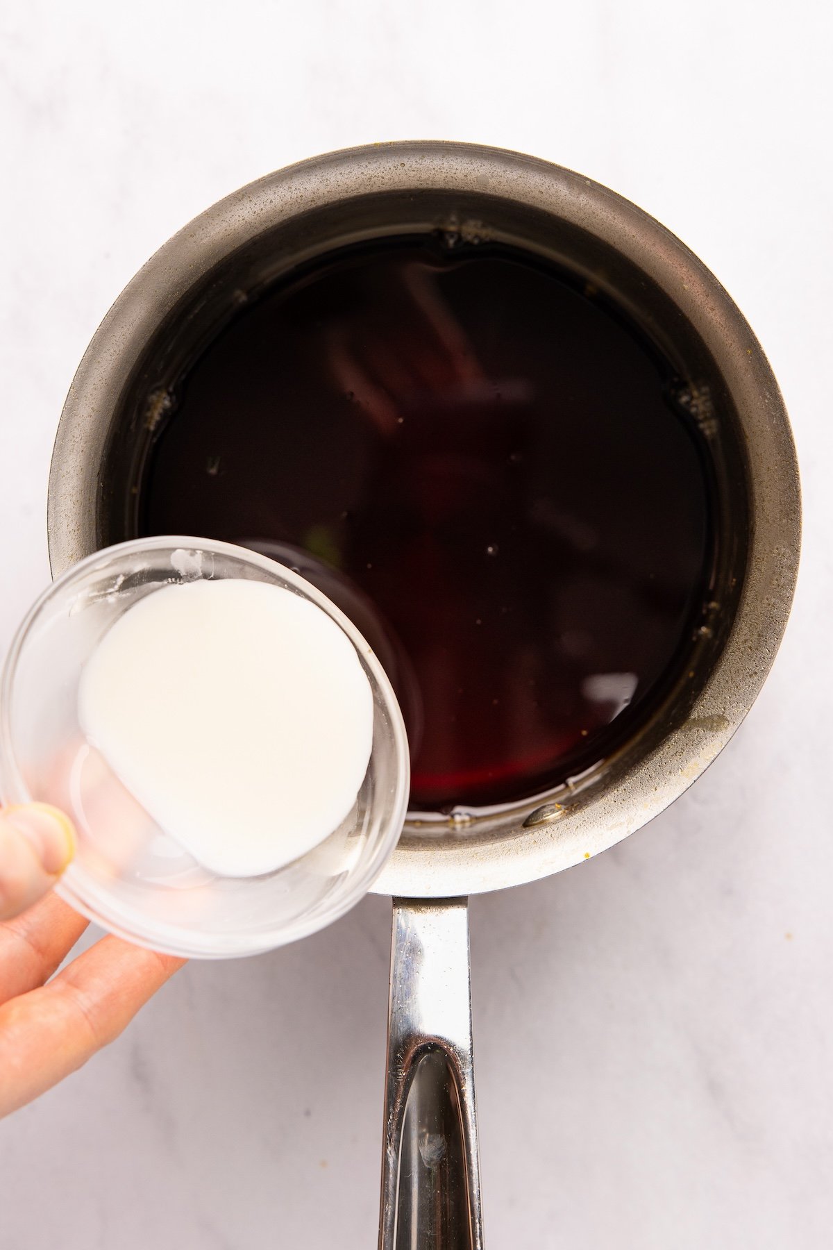 adding cornstarch slurry to sauce in small saucepan