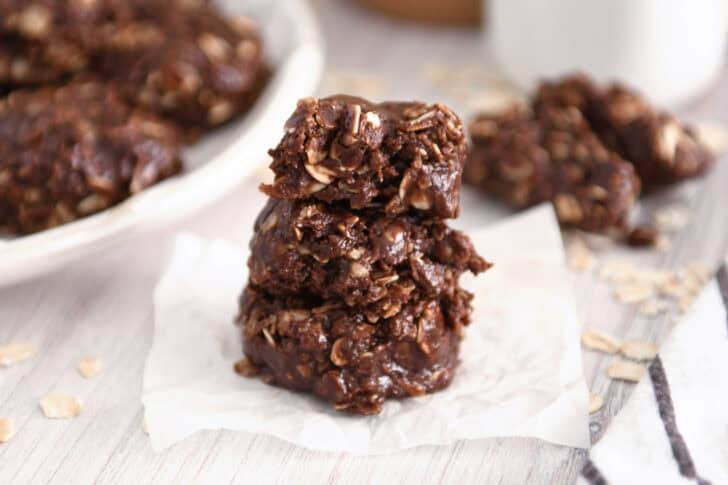 Three chocolate no-bake cookies stacked on parchment.