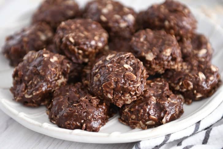 Stack of chocolate no-bake cookies on white plate.