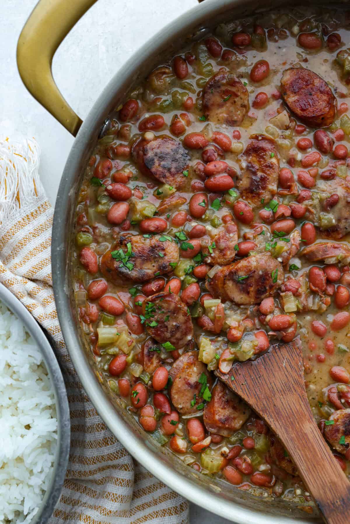 Skillet of red beans and rice with a wooden spoon.