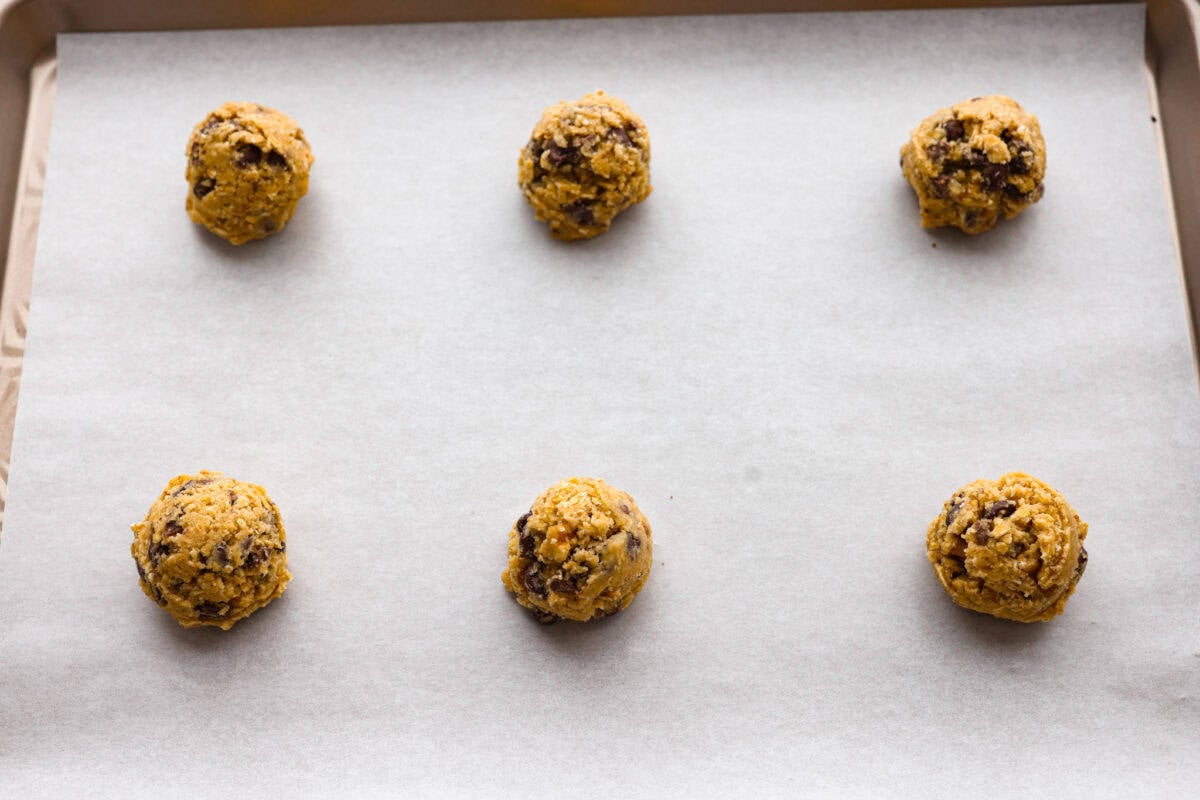 cookie dough balls added to a cookie sheet ready to be baked. 