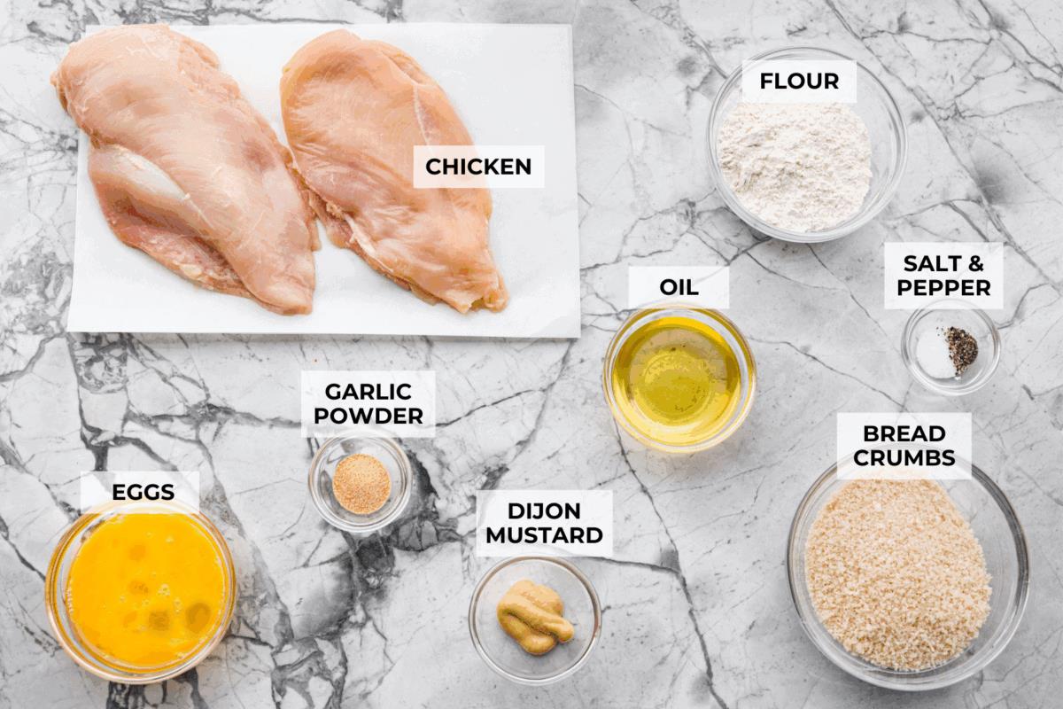 Overhead shot of labeled chicken schnitzel ingredients. 