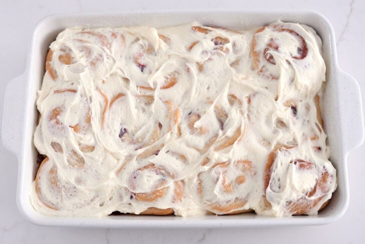 Baked sweet rolls in white 9X13-inch pan spread with sweet cream cheese icing.